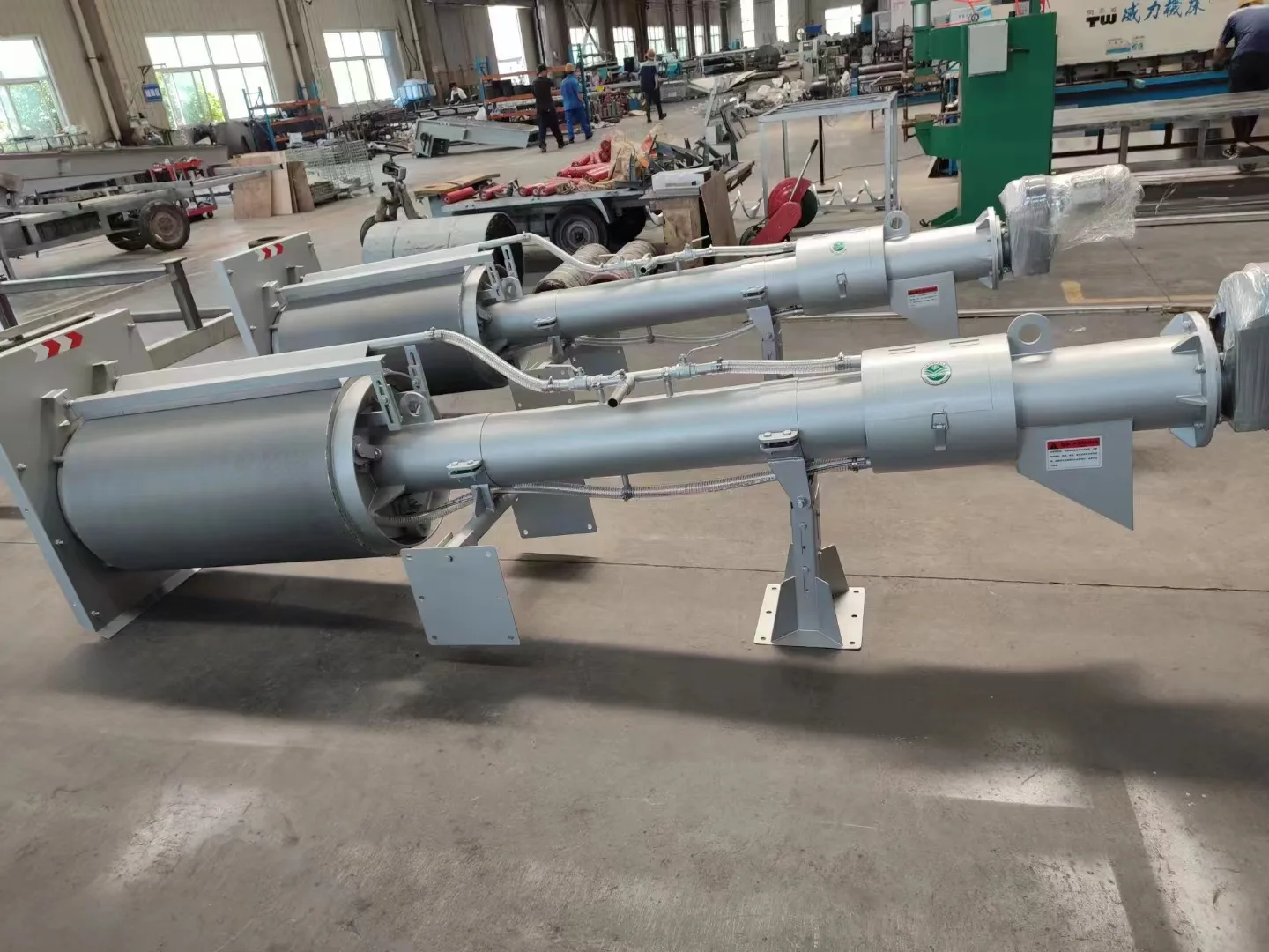 Rotary drum screens on their stands in the workshop, with the drum drive and the support frame